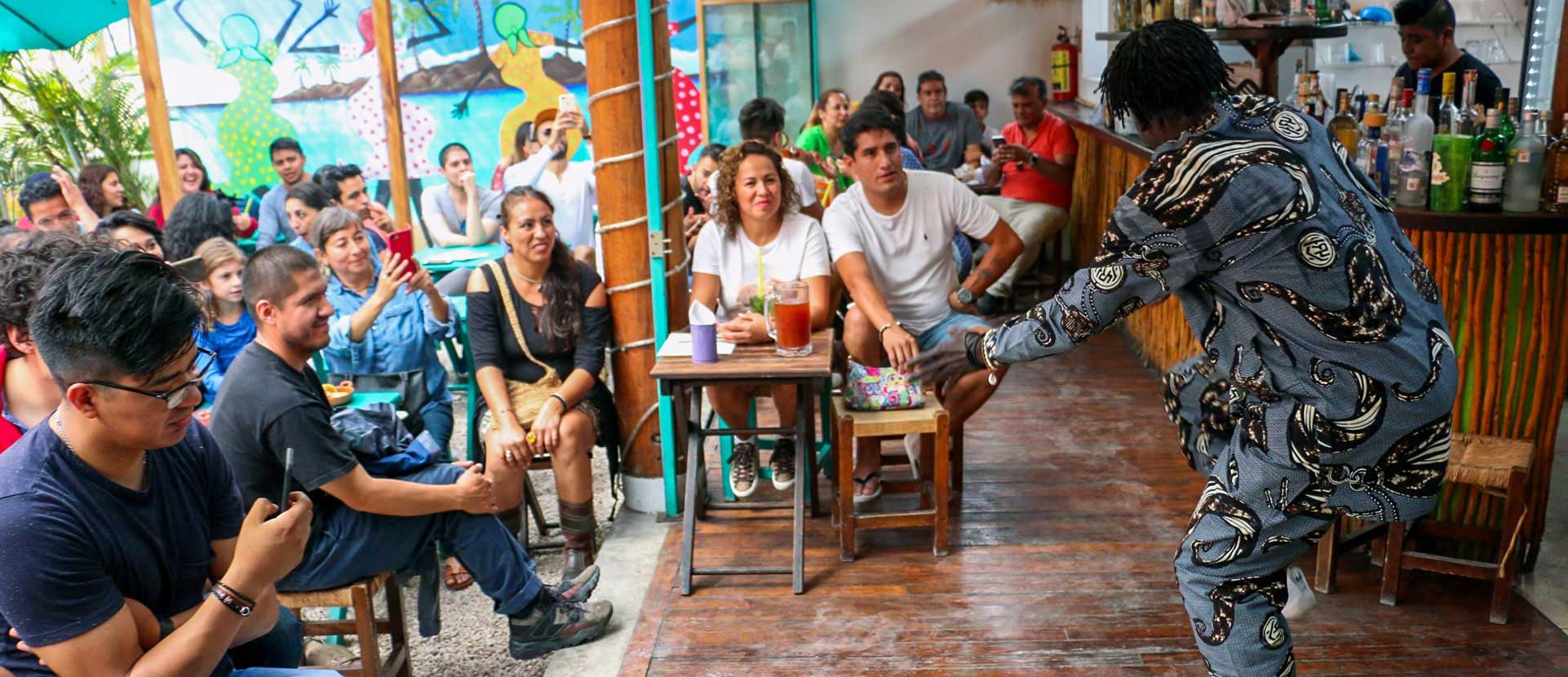 Personas reunidas alrededor de un percusionista en un espacio abierto.